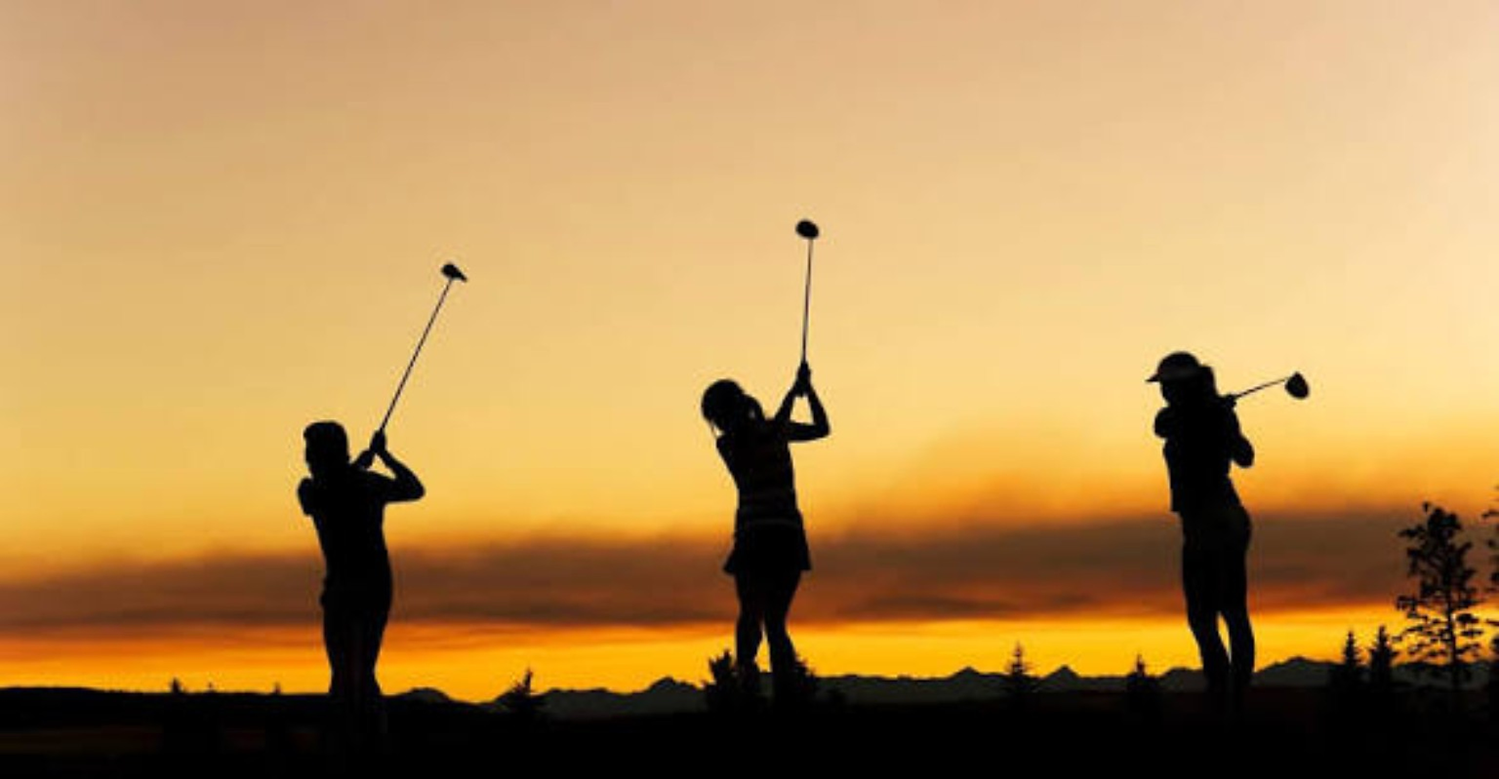 Golfers at the driving range at sunset